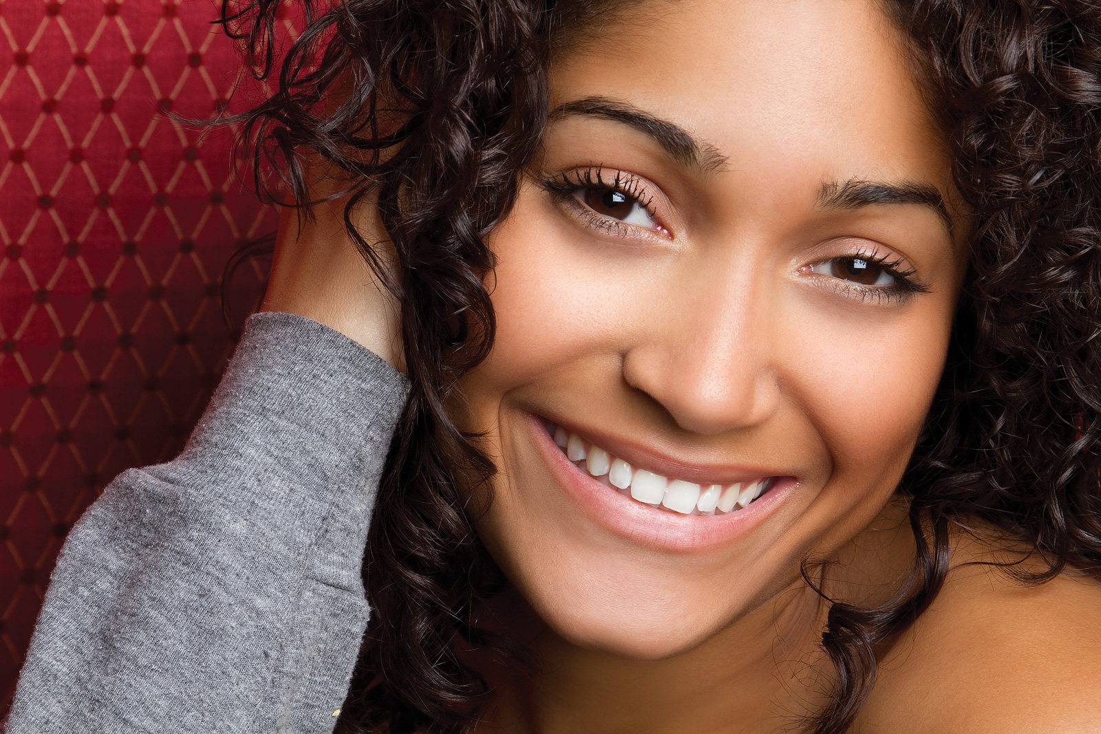 young woman with curly hair posing and smiling, Sterling Heights, MI Cosmetic Dentistry