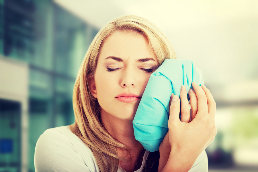 woman with toothache holding ice pack to face needs root canal Sterling Heights, MI